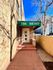Inviting entrance of The Birney apartment building with a charming brick facade and green awning under a clear blue sky.