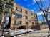 Charming brick apartment building with large windows, surrounded by trees, offering a cozy and inviting urban living experience.