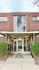 Charming brick apartment entrance showcasing modern design with large windows and inviting greenery.