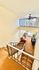 Bright staircase view with elegant railing, cozy seating area, and lush plants beneath a ceiling fan, creating a welcoming ambiance.