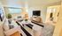 Modern living room with elegant white furniture, striped accents, large windows, and contemporary decor.