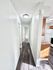 Bright hallway with modern wood flooring leading to spacious rooms, accentuated by natural light and sleek kitchen view.