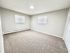 Bright and spacious bedroom with fresh carpeting, neutral walls, and natural light from dual windows.