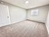Bright, carpeted bedroom with neutral tones, featuring a closed white door and window blinds for a cozy atmosphere.