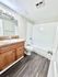 Bright and modern bathroom with sleek dark wood flooring, elegant wooden vanity, and pristine white tub and tiles.