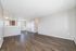 Bright and inviting living space with elegant laminate flooring and a partial view into the kitchen, showcasing modern design and ample natural light.