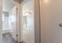 Inviting hallway view showcasing a bright and airy bedroom with soft carpet and a ceiling fan, adjacent to a modern bathroom with sleek floors.