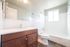 Bright and modern bathroom featuring a sleek wood vanity, pristine bathtub, and elegant tilework.