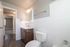 Bright and modern bathroom with elegant fixtures, a sleek wooden vanity, and pristine white tiles, offering a fresh and inviting atmosphere.