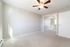 Bright and airy bedroom with plush carpeting, mirrored closet doors, and a modern ceiling fan.