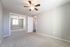 Bright and airy bedroom with plush carpeting, mirrored closet doors, and a modern ceiling fan.