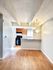 Bright open-concept kitchen with modern lighting, wooden floor, and ample natural light. Ideal for cozy dining and living.