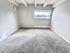 Bright and airy carpeted room with large window, featuring exposed beams and a sleek modern design.