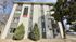 Inviting four-story apartment building with modern exterior and vibrant 'Now Leasing' signage, surrounded by lush greenery and ample natural light.