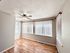 Bright and airy room boasting elegant hardwood floors, large windows with vertical blinds, and a stylish ceiling fan.