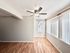 Bright and airy living space with elegant wood flooring and large windows, complemented by a modern ceiling fan for a perfect blend of comfort and style.
