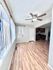 Bright and inviting living area with elegant wood flooring and modern ceiling fan, featuring large windows with vertical blinds in a contemporary open layout.