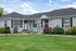 Charming duplex with classic architecture, pristine landscaping, and inviting entryways surrounded by lush greenery.