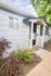 Charming home entrance with vibrant flowers, elegant siding, and welcoming porch under a clear blue sky.