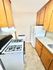 Cozy kitchen with warm wooden cabinets, sleek white appliances, and ample counter space for culinary delights.