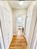 Bright hallway with elegant hardwood floors and built-in storage leading to a modern bathroom with natural lighting.