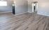 Modern apartment interior with sleek laminate flooring, featuring an open layout with ample natural light and neutral-toned walls.