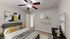 Inviting bedroom with contemporary decor, featuring a stylish queen bed with yellow accents, modern ceiling fan, and elegant artwork on the walls.