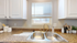 Charming kitchen with stylish countertops, a double sink beneath a sunny window, and modern white cabinetry.