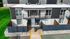 Modern apartment exterior featuring sleek design with balcony, surrounded by well-maintained greenery and secure fencing.