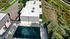 Aerial view of modern apartment complex featuring lush greenery and a sleek swimming pool area.