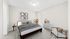 Inviting bedroom with cozy decor, featuring a comfortable bed, modern art, and a large window for natural light, virtually staged.