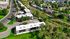 Aerial view of a charming residential community surrounded by lush greenery and well-maintained roads, ideal for a tranquil lifestyle.