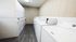 Modern laundry room featuring multiple efficient white washers and dryers, offering convenience and style with sleek wood flooring.