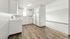 Chic and bright kitchen with sleek white cabinets, modern appliances, and inviting wood flooring leading to a spacious living area.