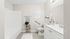 Elegant bathroom with modern fixtures, featuring a sleek white vanity, stylish shelving, and cozy decor. Virtually staged to inspire luxury living.