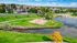 Scenic aerial view of a vibrant community park with a charming pond, lush greenery, and a fenced sports court, perfect for outdoor activities and relaxation.