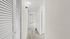 Bright and inviting hallway with modern light fixture, sleek wooden flooring, and crisp white doors, showcasing a stylish apartment interior.