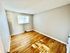 Bright and inviting room with freshly polished hardwood floors and ample natural light from a large window, perfect for a cozy bedroom or home office.