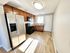 Modern kitchen with stainless steel appliances, warm wood cabinetry, and sleek laminate flooring, bathed in natural light.