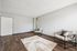 Modern living room with sleek hardwood floors, minimalist chairs, and a stylish geometric rug.