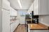 Bright and modern galley kitchen with sleek countertops, ample white cabinetry, and stainless steel appliances enhanced by natural light.