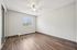 Bright and spacious bedroom with elegant wood flooring, a large window offering ample natural light, and a ceiling fan for comfort.