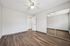Bright and spacious bedroom with elegant wood flooring, mirrored closet doors, and a modern ceiling fan.