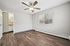 Bright and airy bedroom with modern ceiling fan, large window bringing in natural light, and elegant wood flooring.