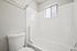 Bright, modern bathroom with sleek white tiles, a spacious bathtub, and a frosted window for natural light.