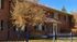 Charming red brick apartment building with a lush autumn landscape and classic wrought iron fence.