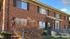 Charming two-story brick building with large windows and manicured bushes, ideal for cozy living.