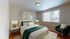 Inviting bedroom with elegant decor, highlighting a plush bed with a green throw and stylish bedside lamps, complemented by large windows for ample natural light.