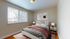 Inviting bedroom with modern decor, cozy natural lighting, and elegant artwork, perfect for relaxation.