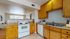 Bright, inviting kitchen with modern appliances, ample wooden cabinetry, and open view to cozy living space.